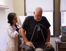 A doctor uses her stethoscope to listen to a patient's heart 