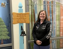 Dr. Chelsea Collins standing next to cancer-free bell