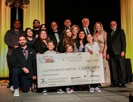 sponsoring family stands with CH administrators and three smiling kids, holding giant check