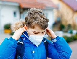 Young boy removing medical face mask