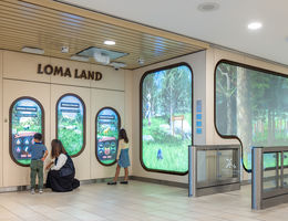 two children and a mother-figure interacting with a digital wall-type animation in a hospital lobby.