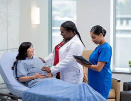 Pregnant woman on hospital bed next to doctor and nurse