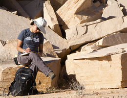 Sarah Maithel, the Loma Linda University graduate student who may know more about Coconino Sandstone than anyone else in the world, sits on a pile of the buff-colored stone to annotate her findings. Sarah Maithel annotates her findings while sitting on a slab of Coconino Sandstone