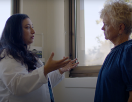 Halley Vora, MD, director of Breast Health Services, outlines treatment options patients should consider before discussing with their provider. Doctor with brown hair in white coat has a conversation with a patient wearing blue top with short blonde hair.