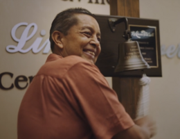 Hoy en día, el cáncer de Jose Espinoza sigue controlado. Un hombre está tocando una campana con entusiasmo.