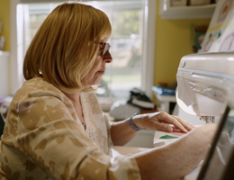A woman is sitting in a chair using a sewing machine