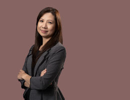 Asian woman in black and white business suit standing with arms crossed