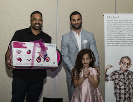 father stands with daughter while she is presented with bike