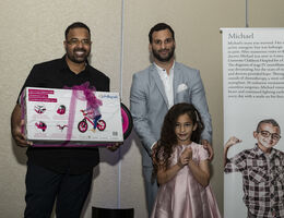father stands with daughter while she is presented with bike
