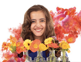 teenage caucasian female smiles in front of vases of flowers