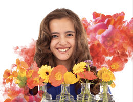 teenage caucasian female smiles in front of vases of flowers