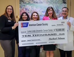 Five people hold giant presentation check