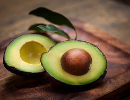 Avocado cut in half on a wood cutting board.