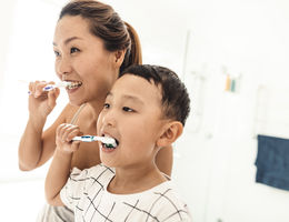 mom with son brushing teeth