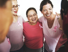 Group of women standing in a circle with their hands over each other's shoulders