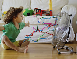 Child sitting in front of fan inside home