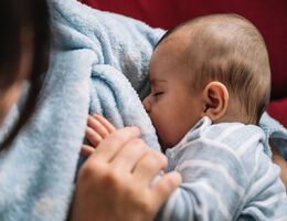 Mother breastfeeding her baby on the sofa
