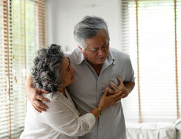 man holding his chest while woman comforts him