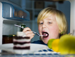 child eats cake out of the fridge