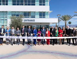 LLUH leaders pose for photo behind long ribbon with large scissors