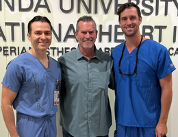 two male doctors stand together with a male patient smiling