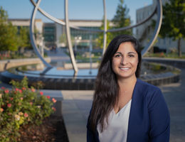 female stands outside smiling in front of fountain