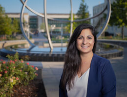 female stands outside smiling in front of fountain
