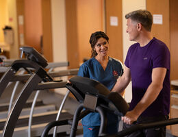 Healthcare provider observing patient walking on treadmill
