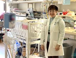 Dr. Elba Simon-Fayard stands in front of NICU crib