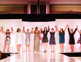 women stand on stage holding hands