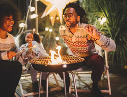 happy family roasting marshmallows in backyard fire pit