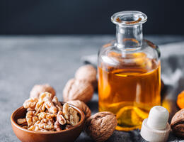 walnuts spread around a small glass bottle of oil.
