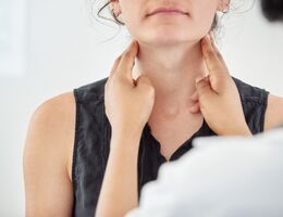 Doctor checking thyroid of a young patient in clinic