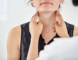 Doctor checking thyroid of a young patient in clinic