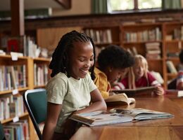 Happy girl reading book in library