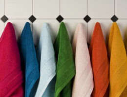 Multi colored towels hanging in a row on the wall 