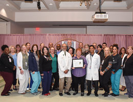 Group of doctors and staff stand in a large group holding an award