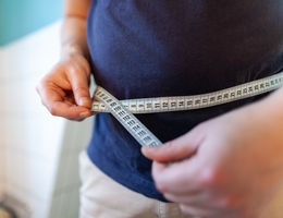 Man holding a measuring tape to his waist