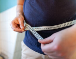 Man holding a measuring tape to his waist