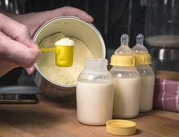 Hand holding scoop of powdered baby formula, ready to mix in bottles stock photo
