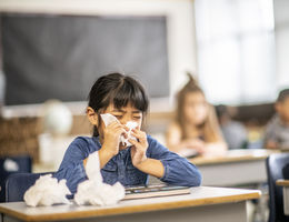 Multi-ethnic group of school children. One child sick with tissues. 