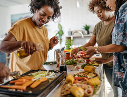 Group of female friends making vegetarian lunch in the kitchen at apartment together