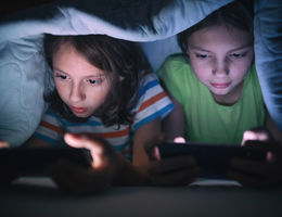 Boy and girl playing games on mobile phone in their bed stock photo