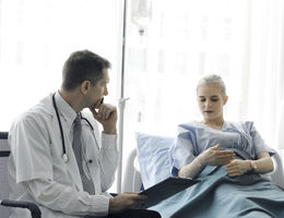 Doctor doing a physical examination of the young beautiful patient and explaining health problems to the patient who lying on the hospital bed, health care and hospital concept stock photo