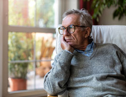 Sad white man staring out the window lost in his thoughts (stock image)