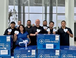 Group of individuals standing outside with blue boxes holding paper hearts.