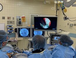 Three doctors in an operating room looking at the screen