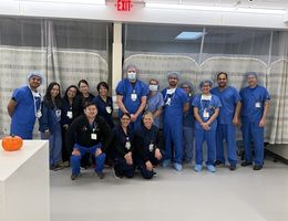 Large team stand and kneel in scrubs for group photo