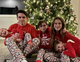 Elijah sitting with his siblings by Christmas tree