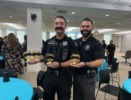 Two officers stand side by side holder trophies, smiling